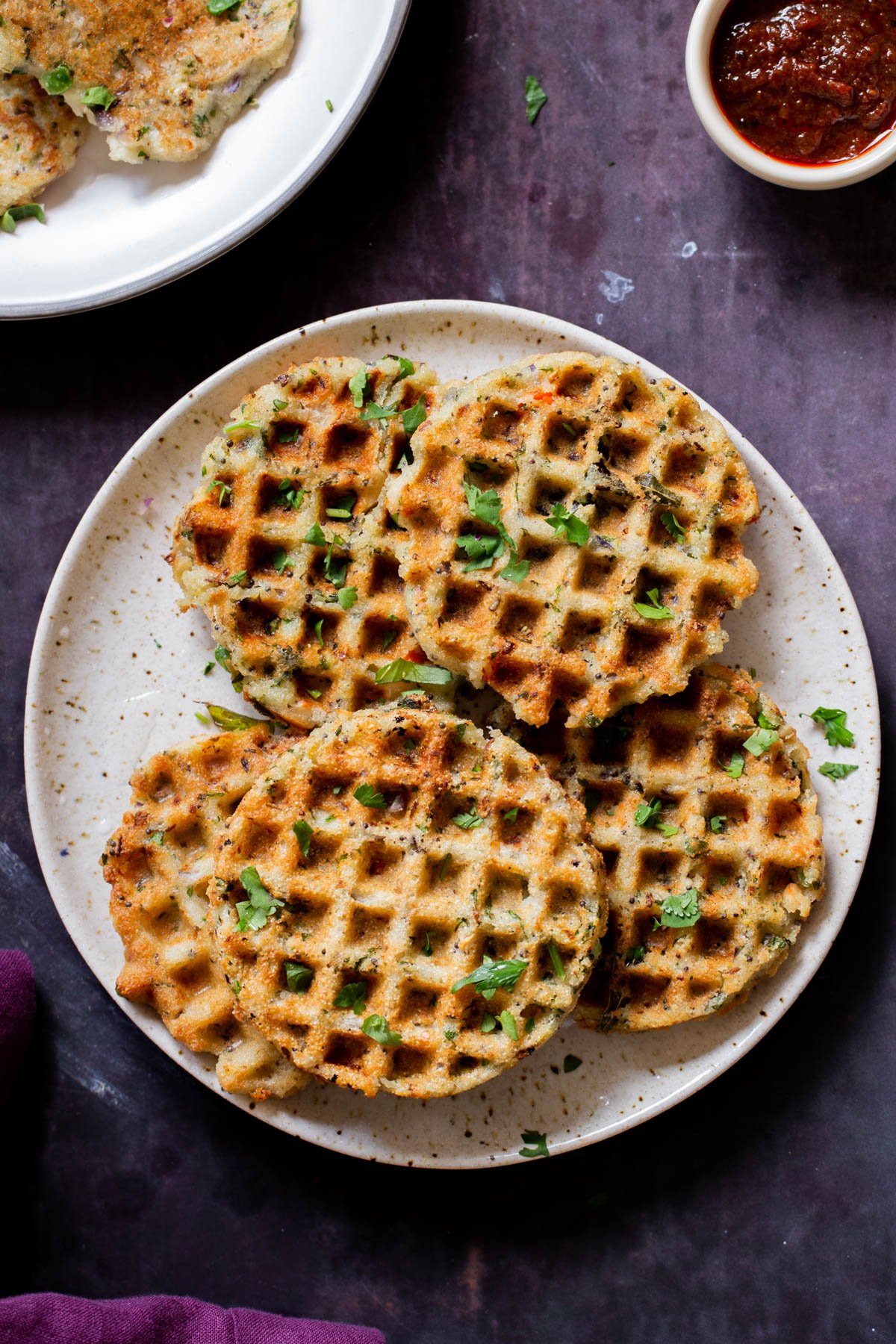 plates of rava idli waffles and pancakes next to a bowl of chutney