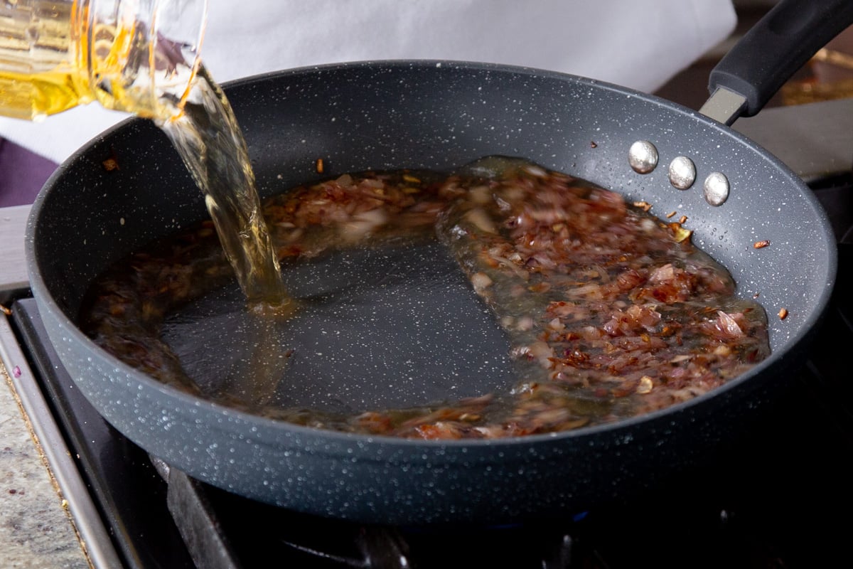 adding water and spices to the frying pan