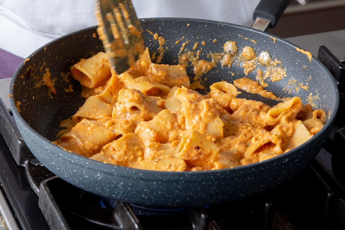 pasta in a skillet after tossing with the romesco sauce