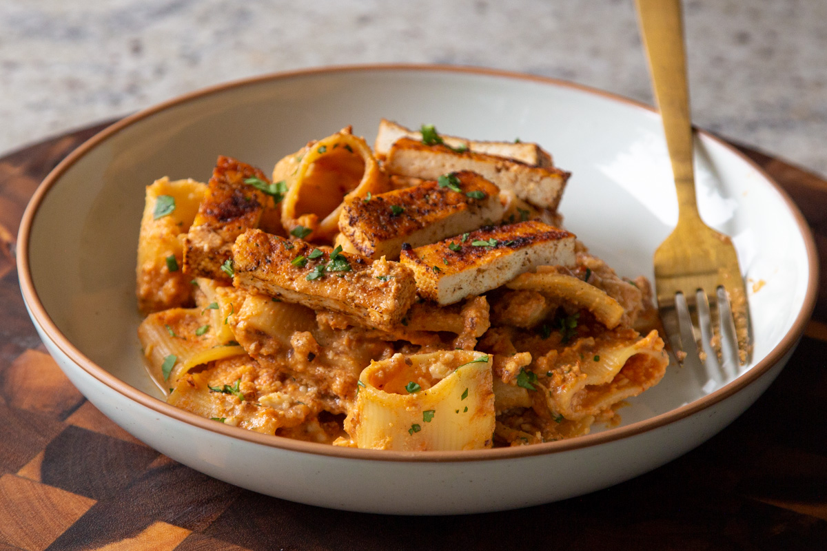 romesco sauce pasta in a bowl with cajun tofu on top