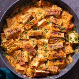 romesco pasta in a skillet with cajun tofu on top