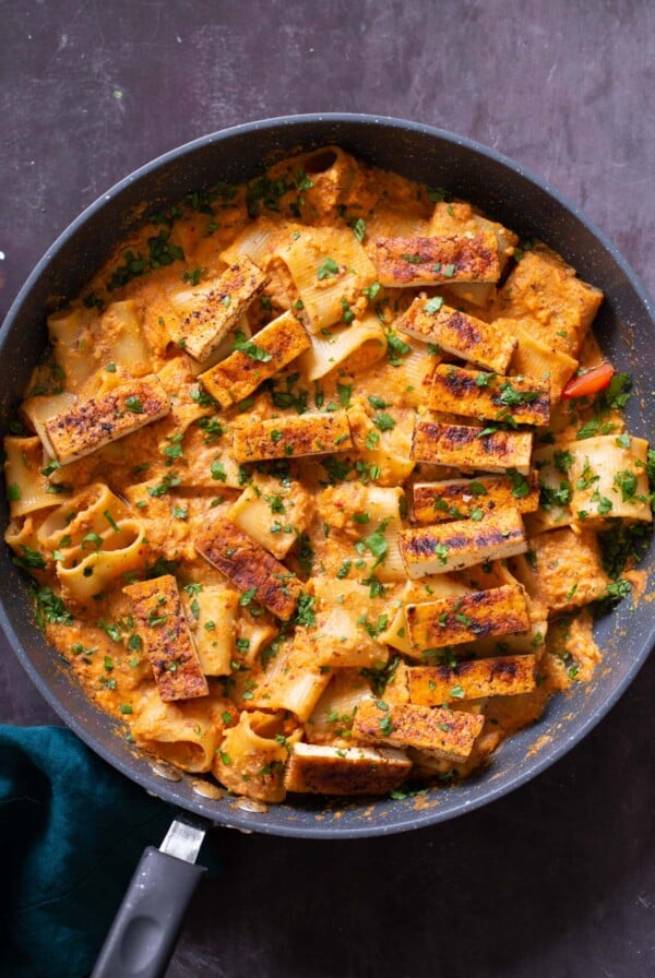 romesco pasta in a skillet with cajun tofu on top