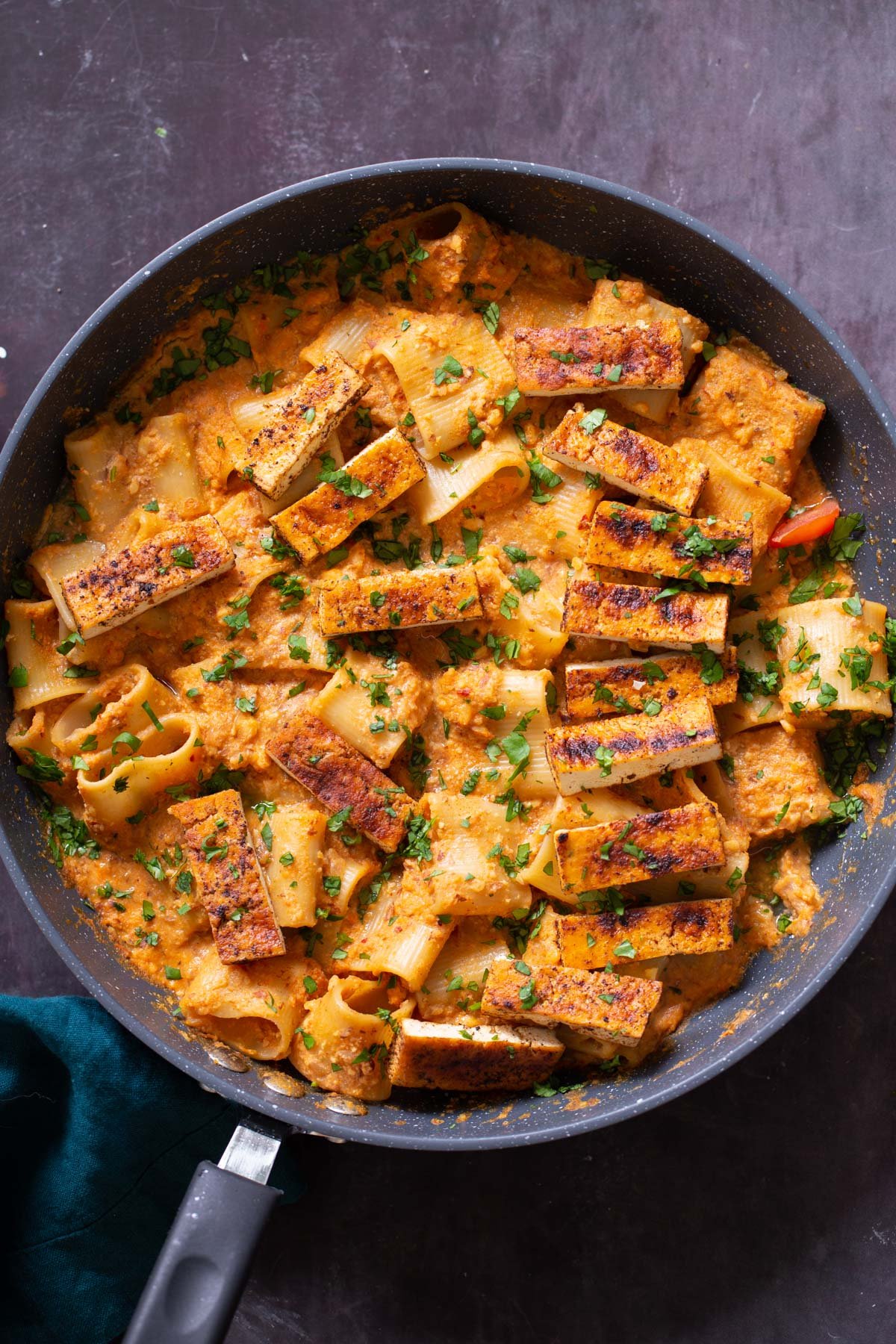 romesco pasta in a skillet with cajun tofu on top