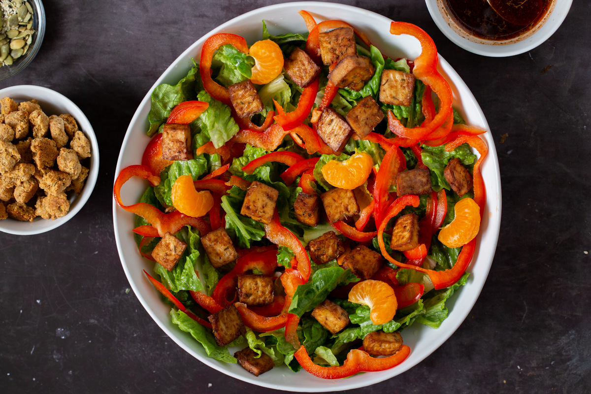 adding orange sections to the salad bowl