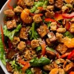 close-up of vegan summer salad in a bowl with tofu, croutons, veggies and oranges