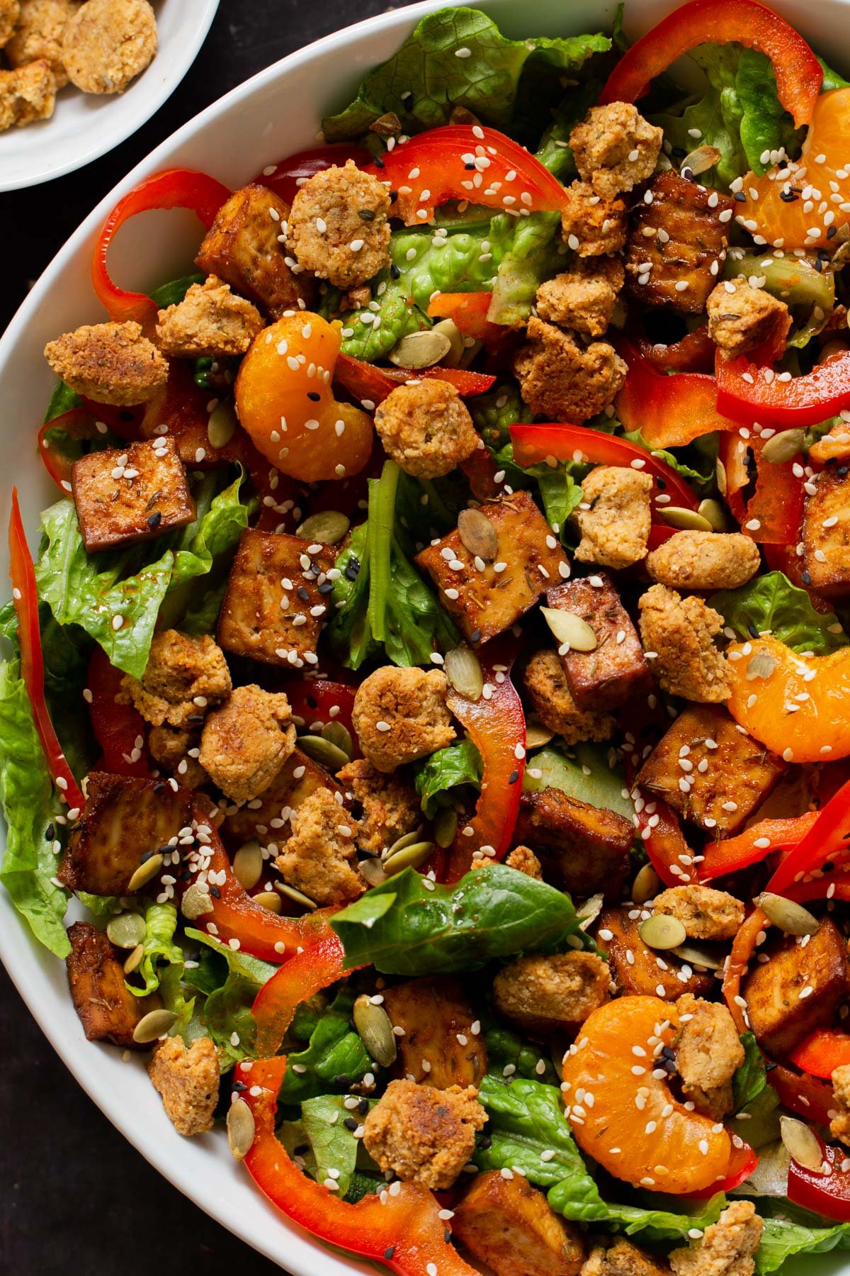 close-up of vegan summer salad in a bowl with tofu, croutons, veggies and oranges