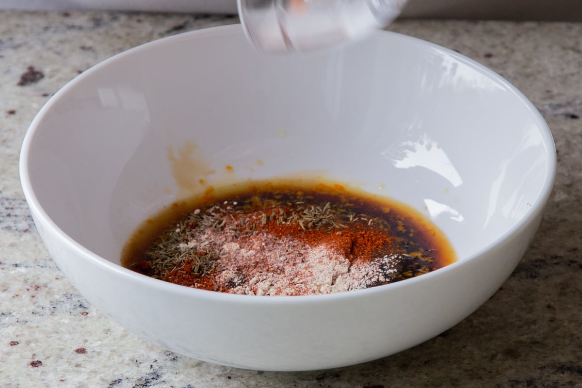 adding dressing ingredients to a large mixing bowl