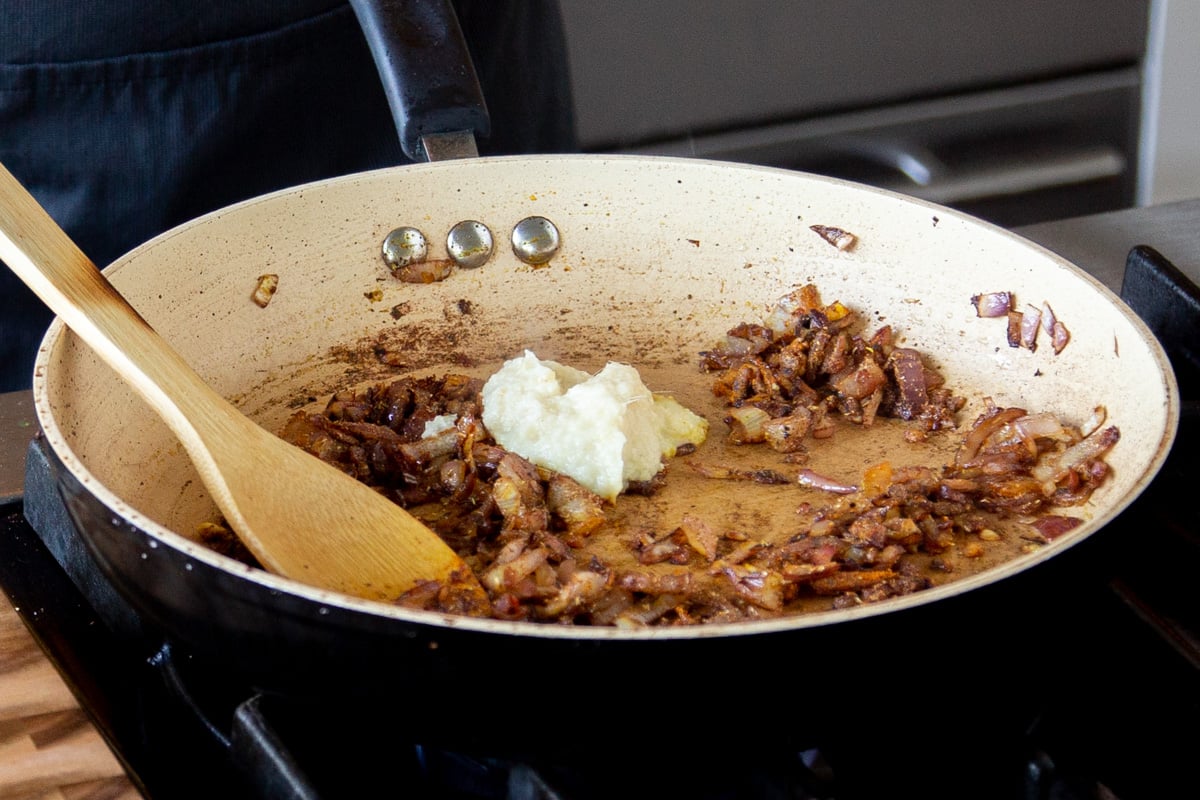 adding ginger-garlic paste to the pan of cooked onions