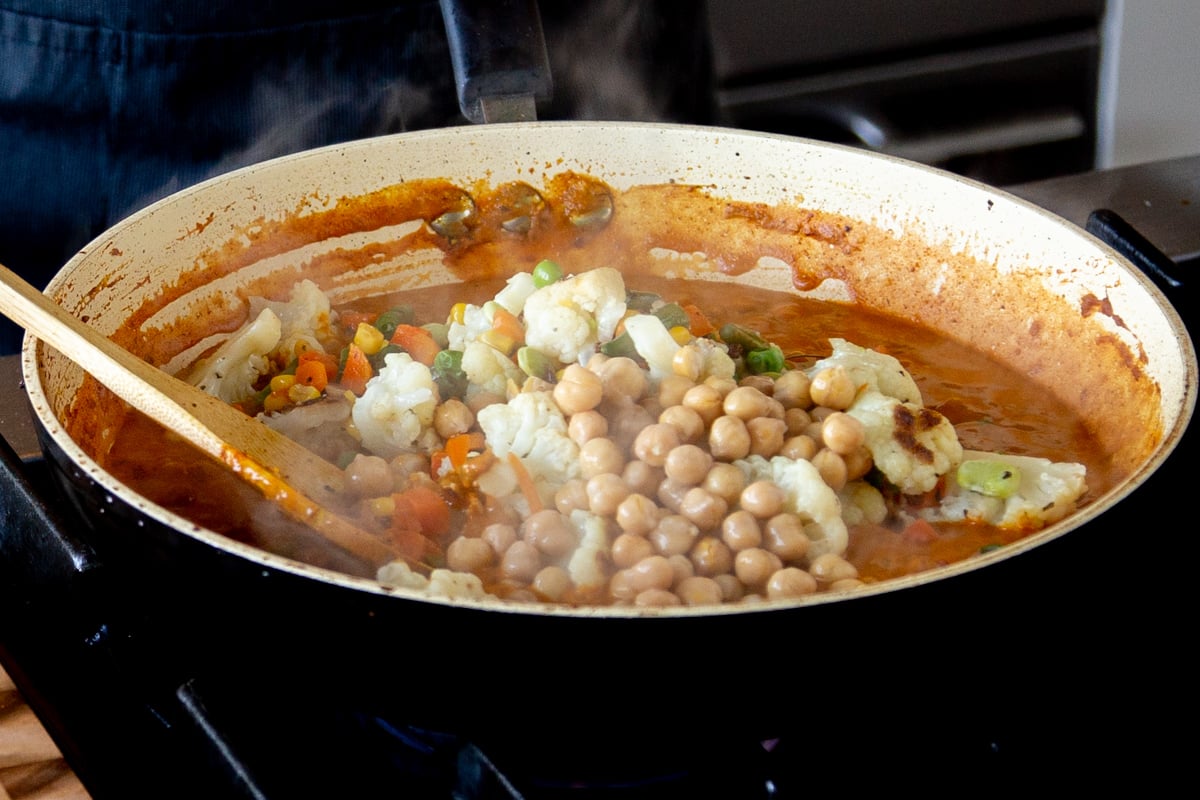 adding veggies and chickpeas to the pan