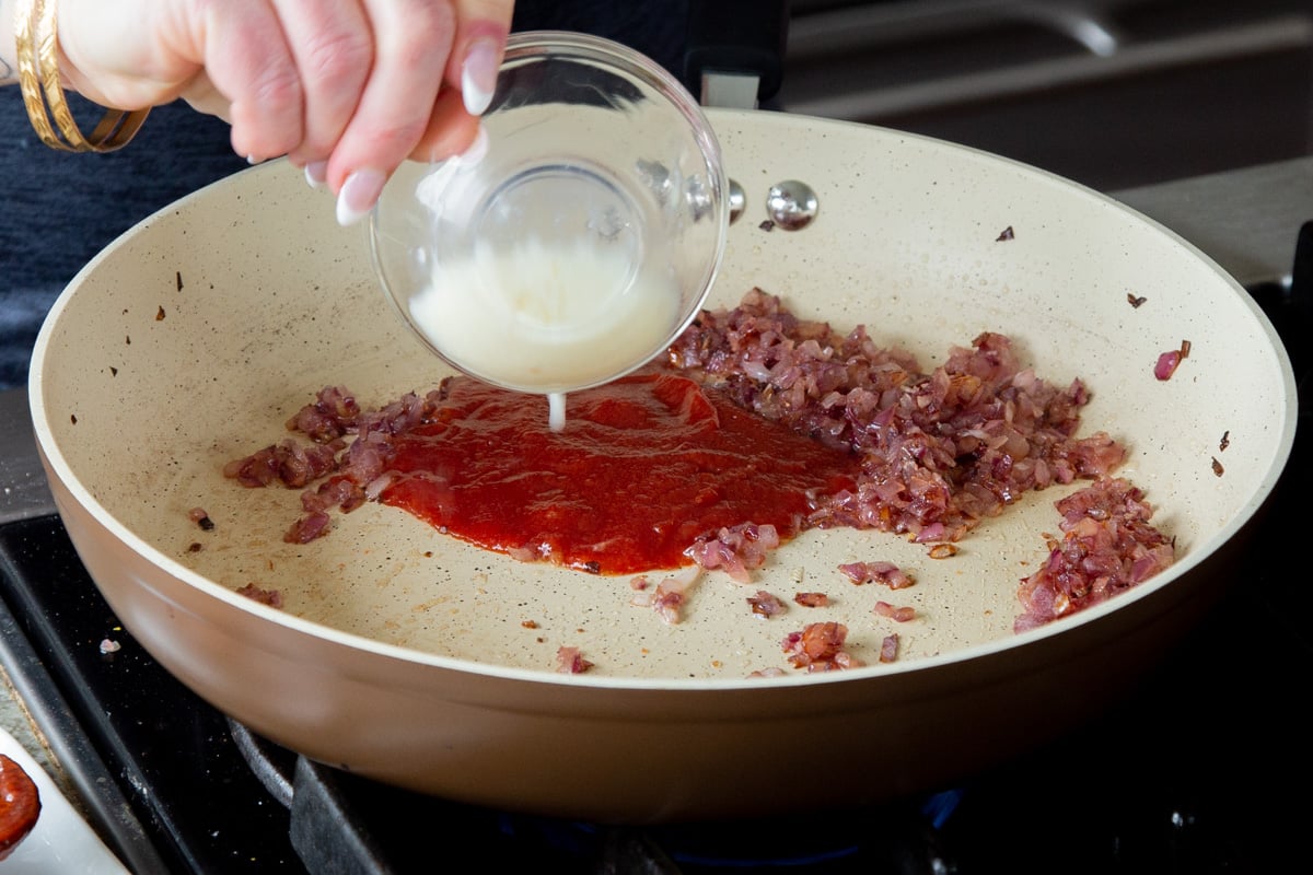adding ketchup and ginger-garlic paste to the cooked onion in the pan