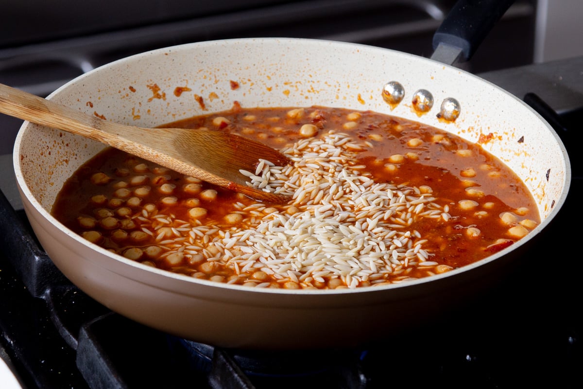 adding orzo and broth to the pan