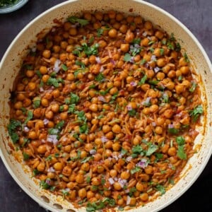 cajun orzo chickpeas in the pan after cooking with fresh herbs and onion on top