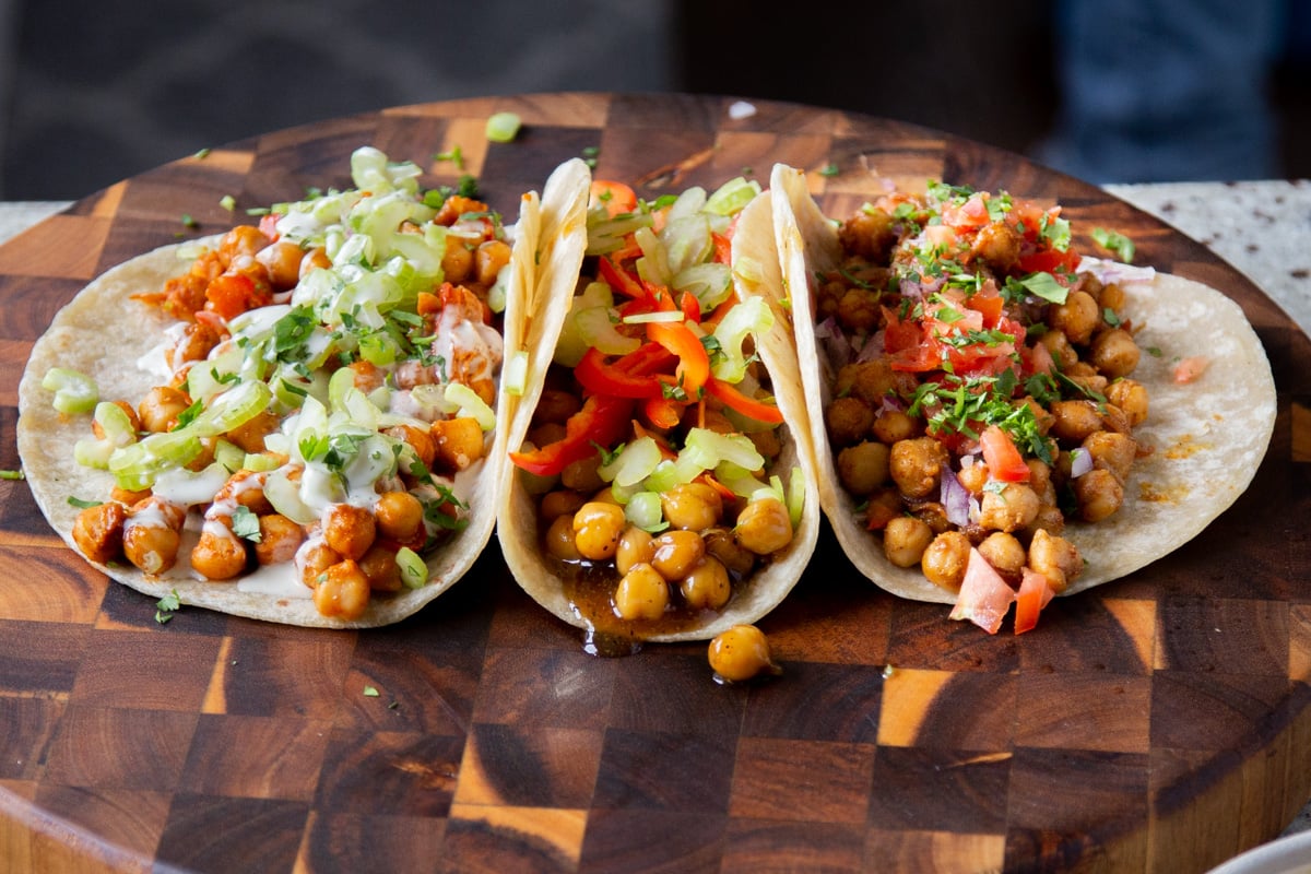 all 3 styles of chickpea wraps with the toppings on a wooden counter