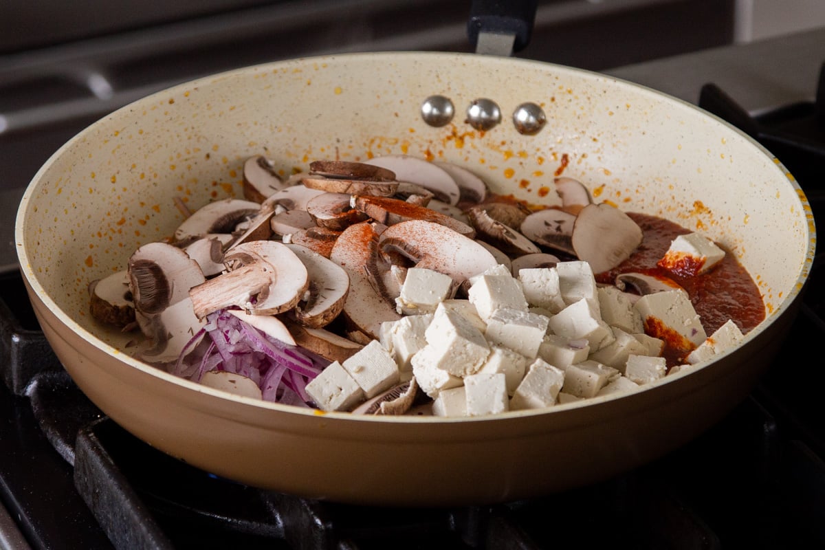 tofu, mushrooms, and onions in the frying pan