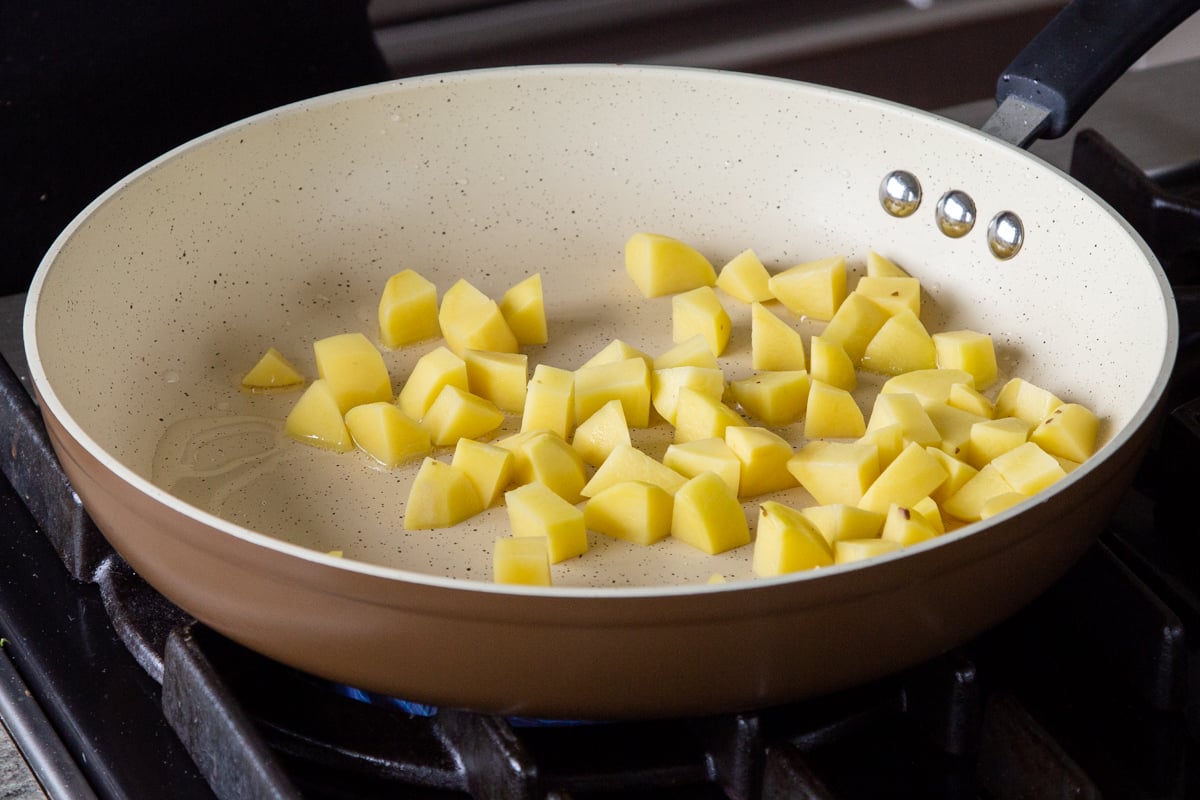 adding cubed potatoes to the pan