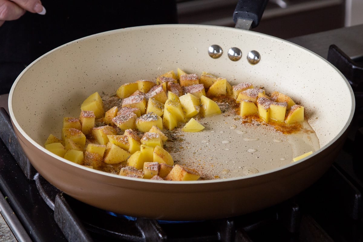 adding spices to the cubed potatoes