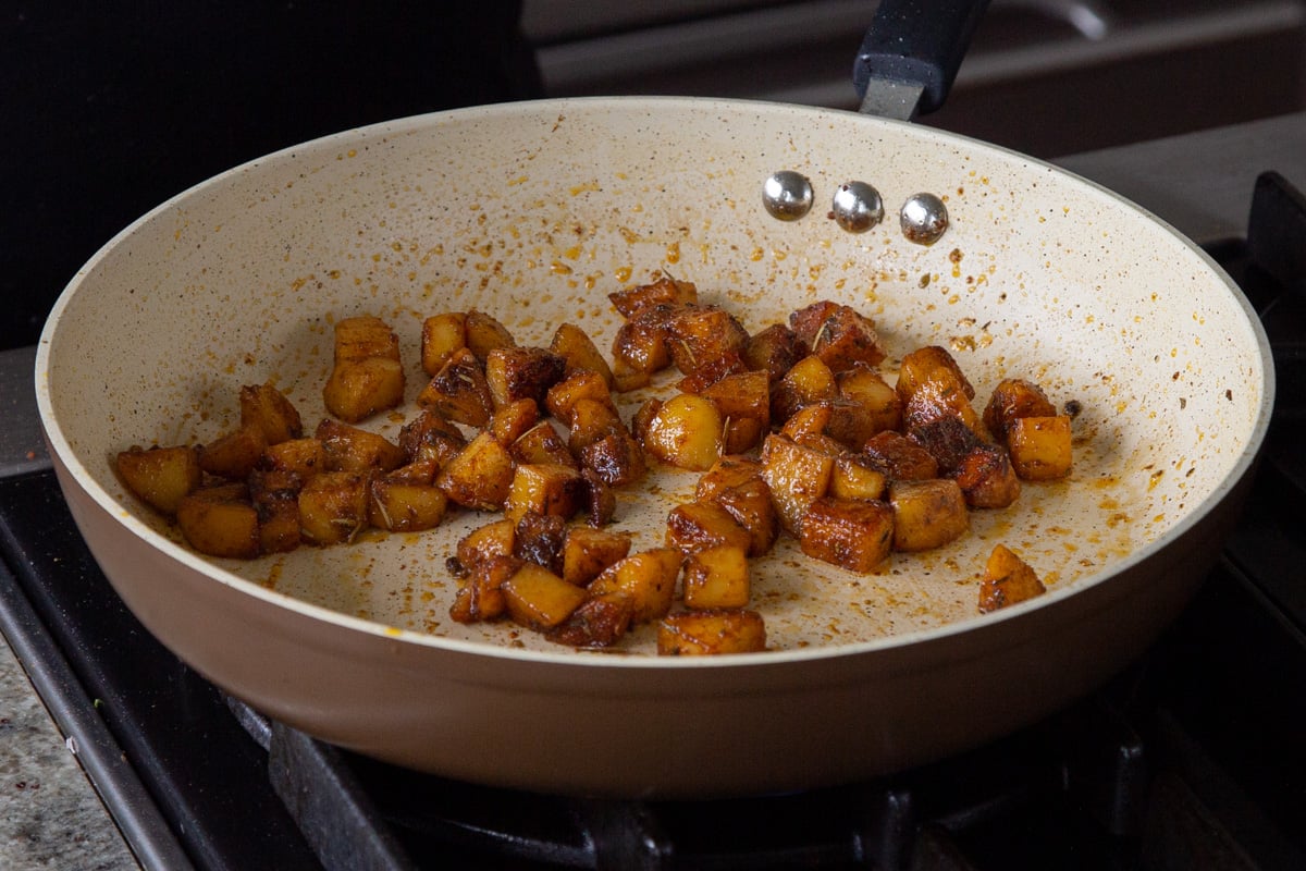 spicy potatoes cooking in the pan with the lid off