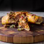 crispy tofu burrito on a wooden cutting board, cut in half so you can see the filling