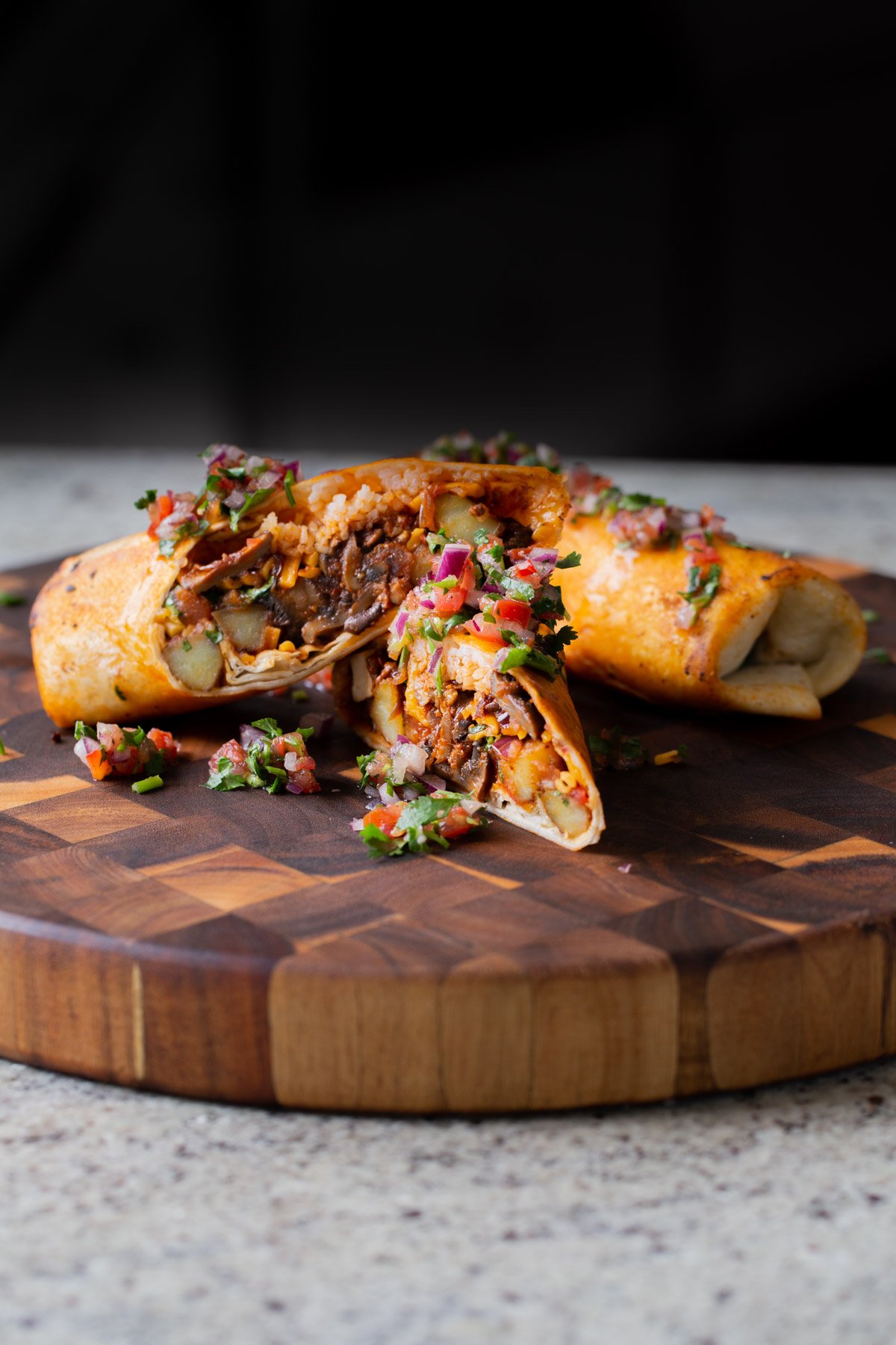 crispy tofu burrito on a wooden cutting board, cut in half so you can see the filling