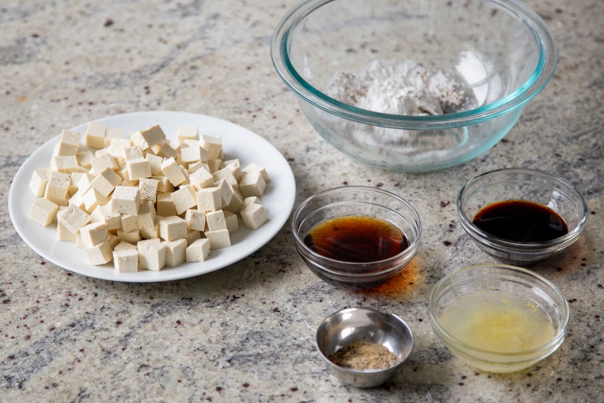 tofu, lemon juice, and other ingredients in bowls on the kitchen counter