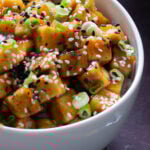 close-up of a bowl of lemon pepper tofu topped with sesame seeds and green onions