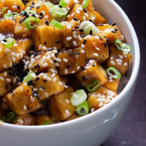 close-up of a bowl of lemon pepper tofu topped with sesame seeds and green onions