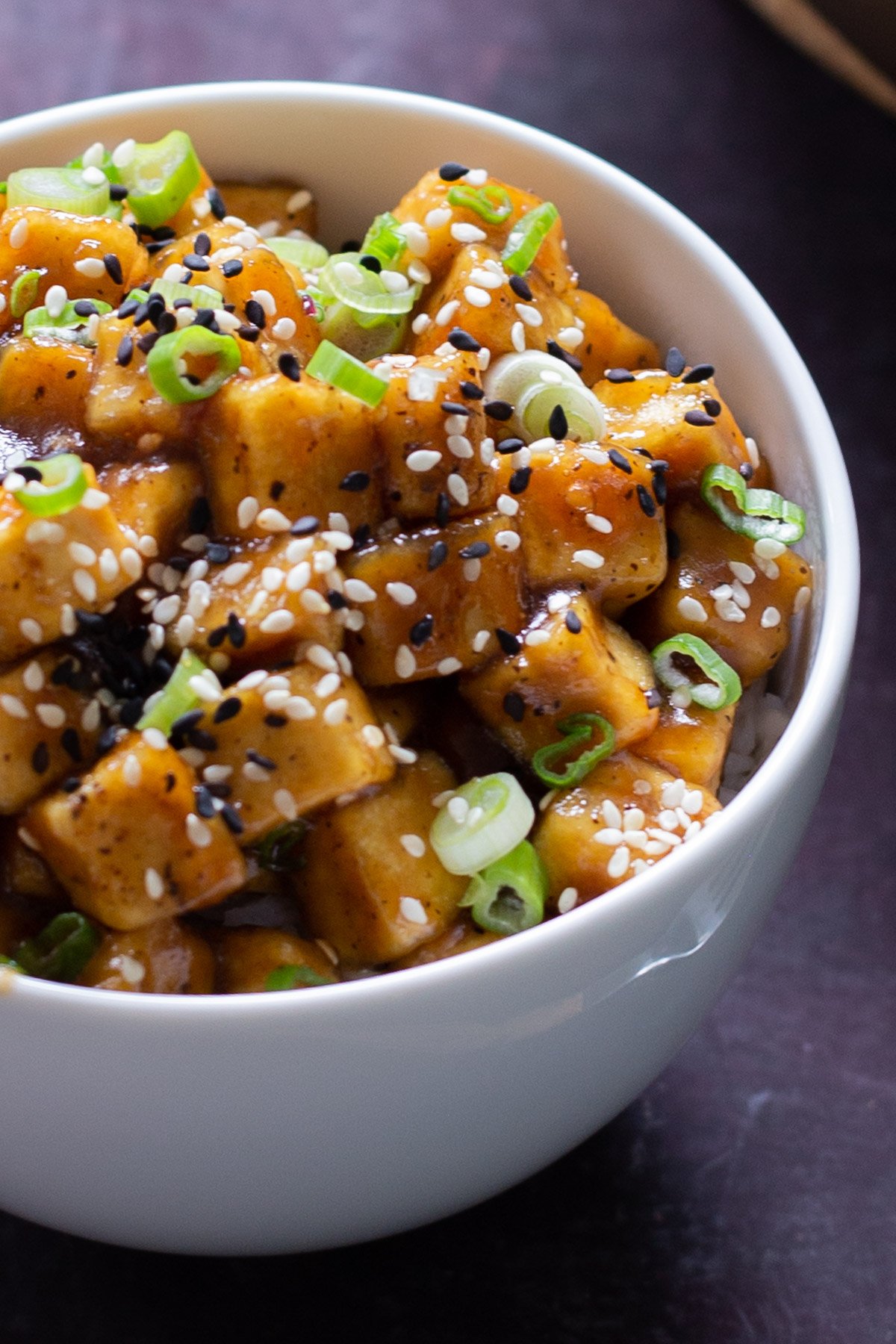 close-up of a bowl of lemon pepper tofu topped with sesame seeds and green onions