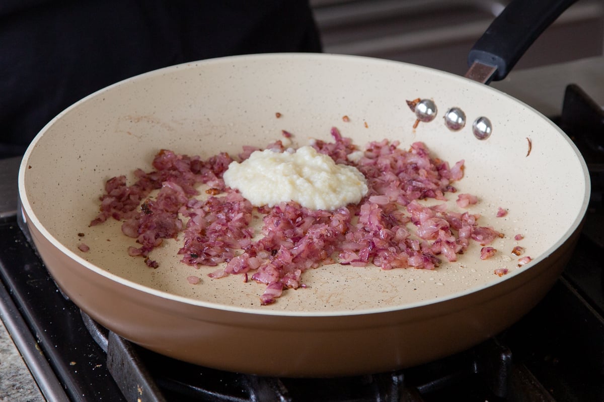 adding ginger-garlic paste to the cooked onions in the pan
