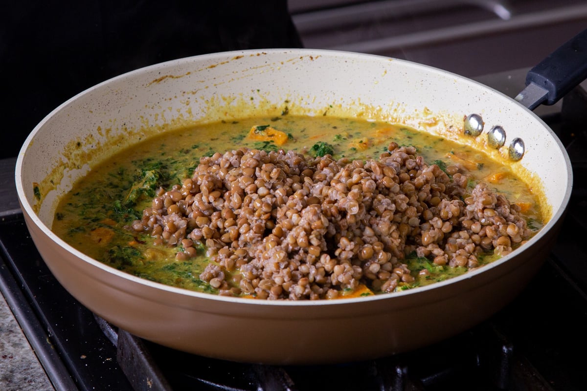 adding lentils to the pan of curry