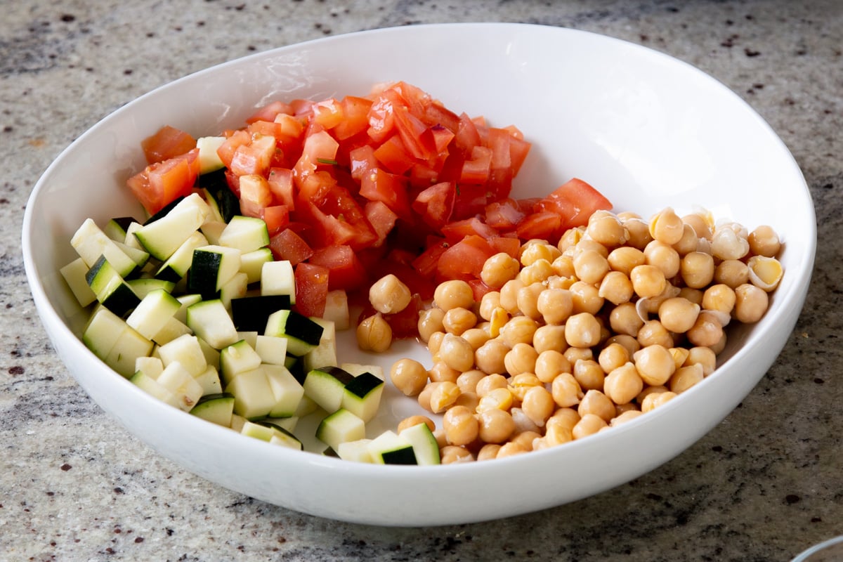 adding chickpeas to the salad bowl