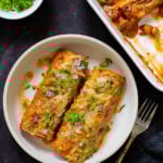 butter chicken enchiladas on the plate next to the baking pan