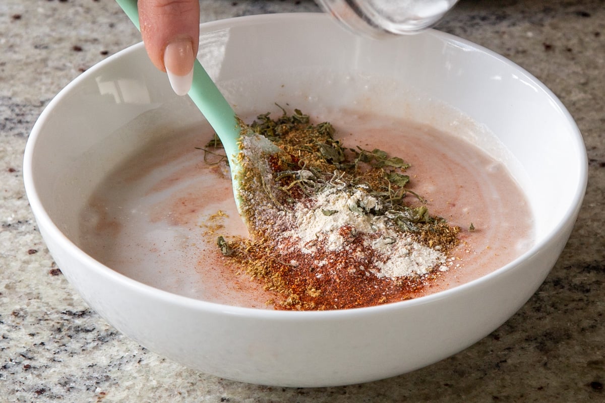 spices added to a bowl with coconut milk and tomato paste