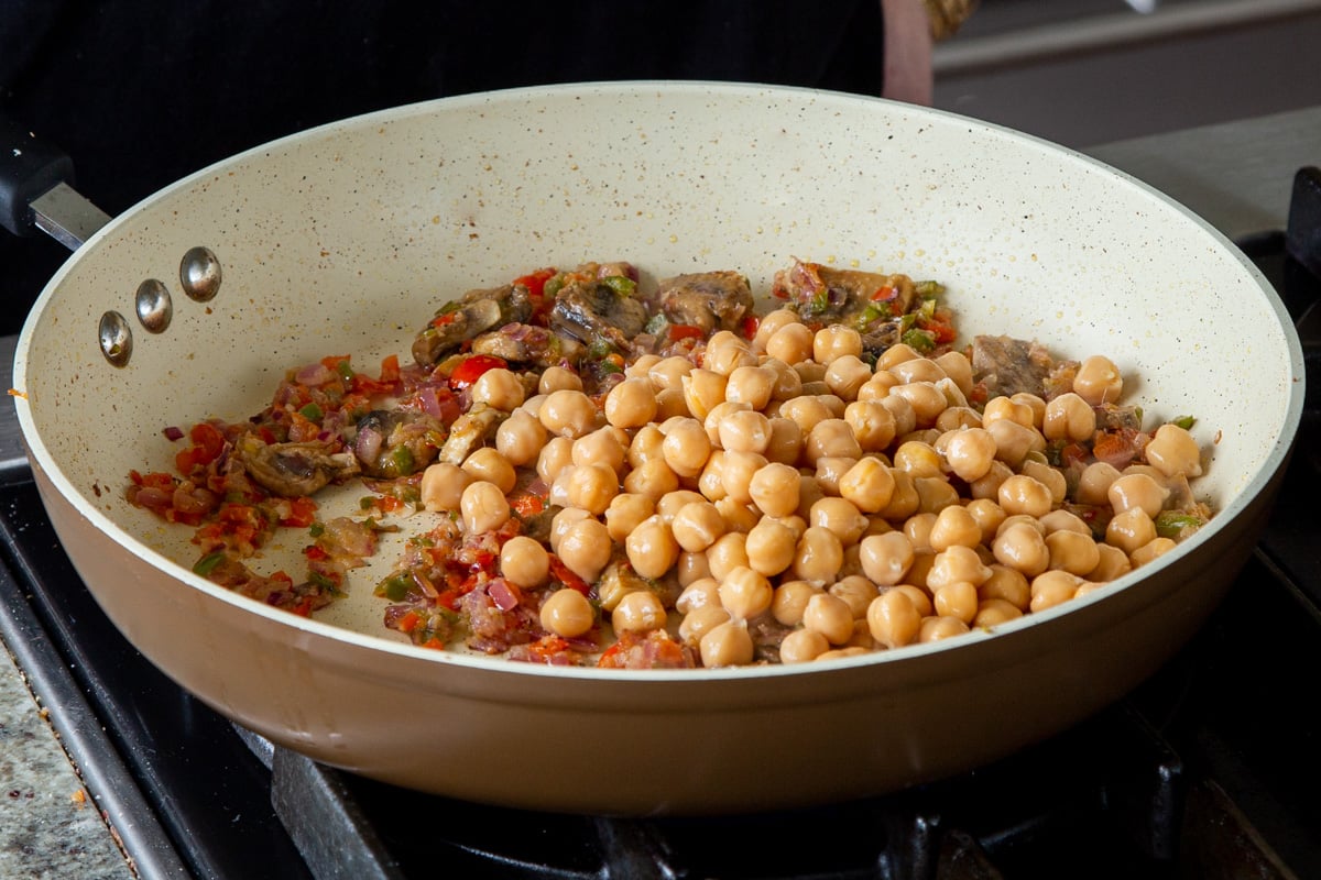 adding chickpeas to the pan of cooked aromatics