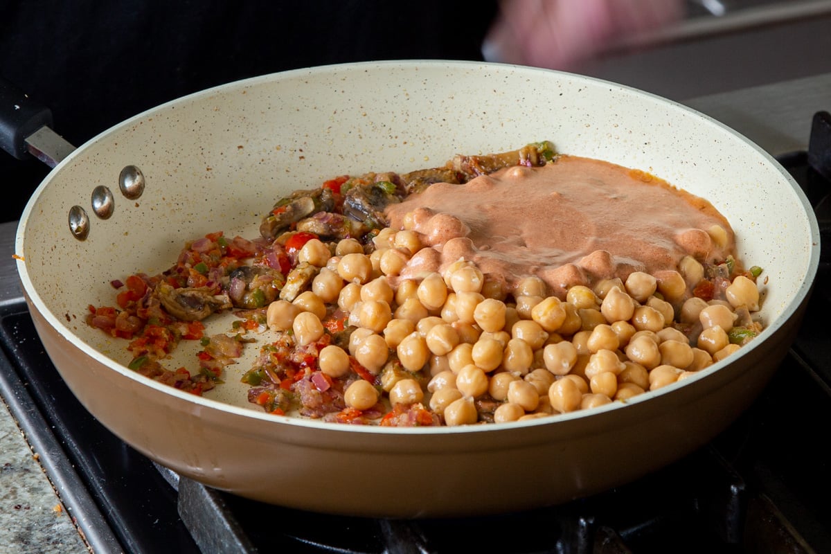 adding remaining filling ingredients to the pan with the chickpeas