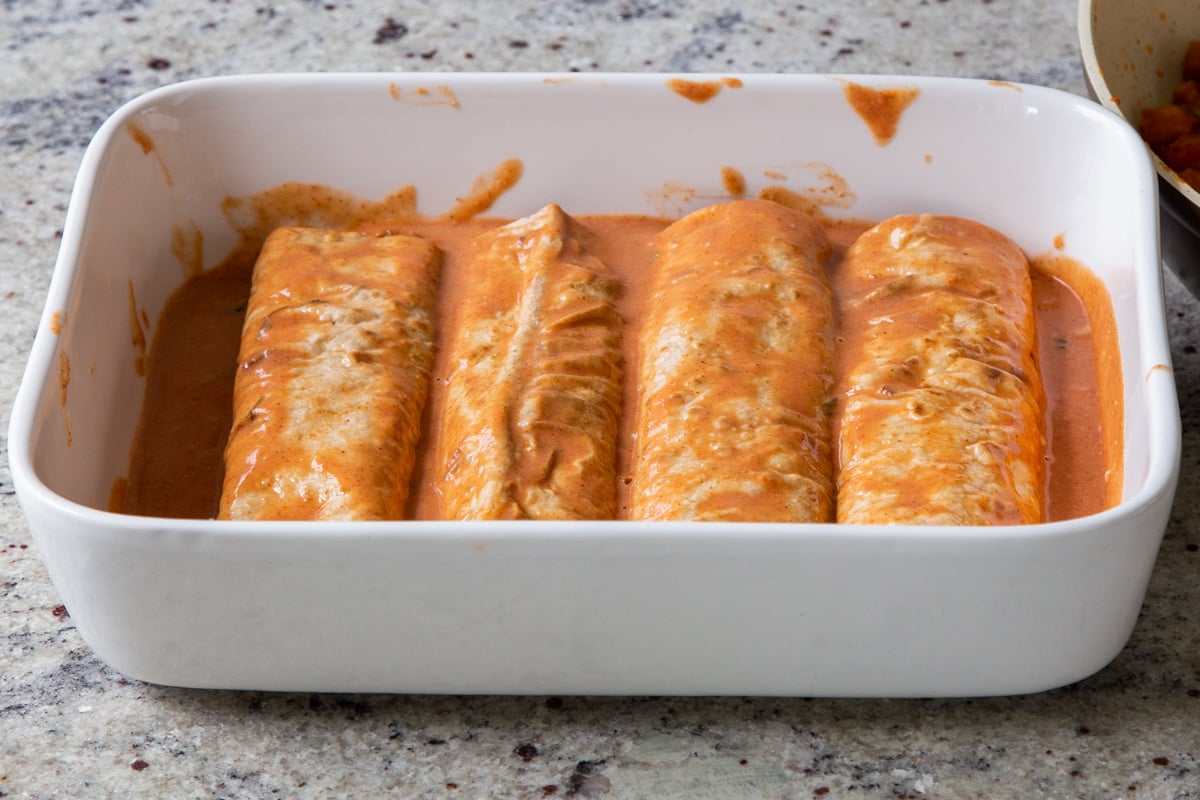 rolled enchiladas in the pan, toped with butter chicken sauce