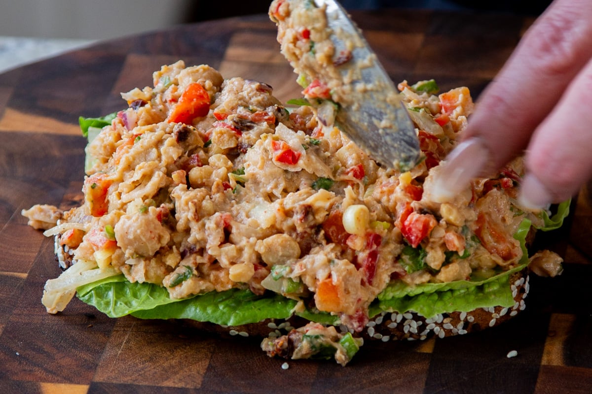 sponging cajun chickpea salad over the lettuce on the slice of bread