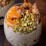 cannoli overnight oats in a glass topped with oranges, pistachios, and crispy cinnamon sugar tortilla pieces