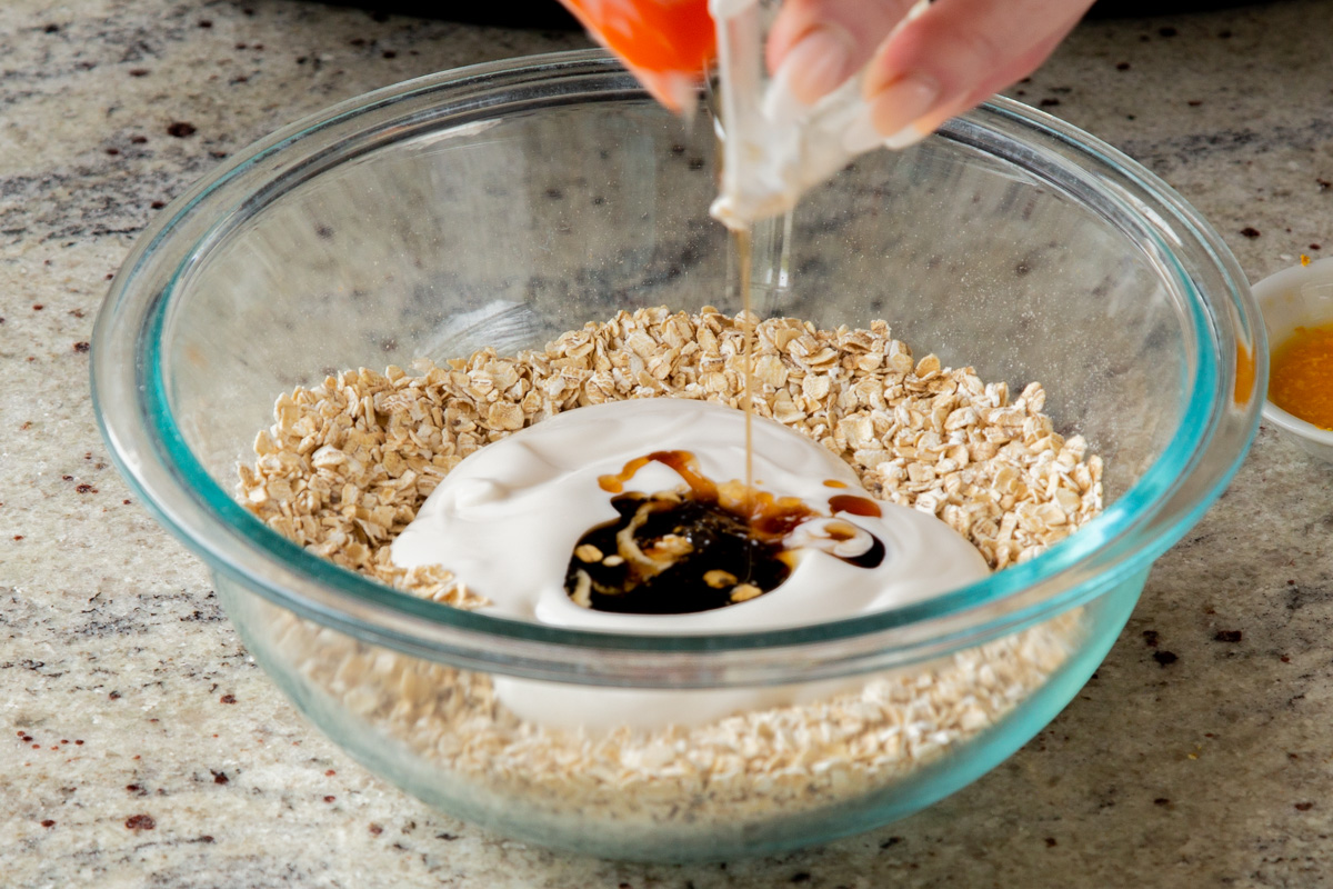 adding yogurt and maple syrup to the dry oat mixture