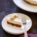slice of carrot cake cheesecake on a plate next to the full cake