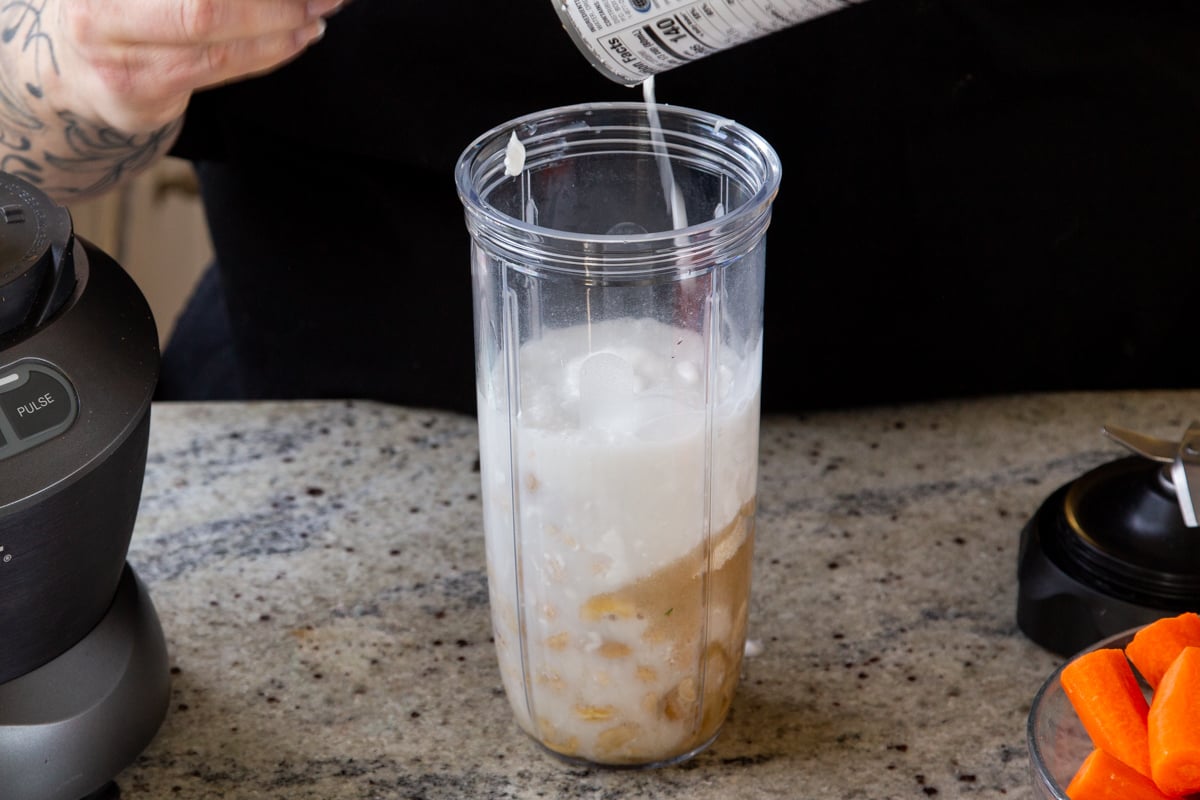 adding coconut milk to the cheesecake layer ingredients to the blender