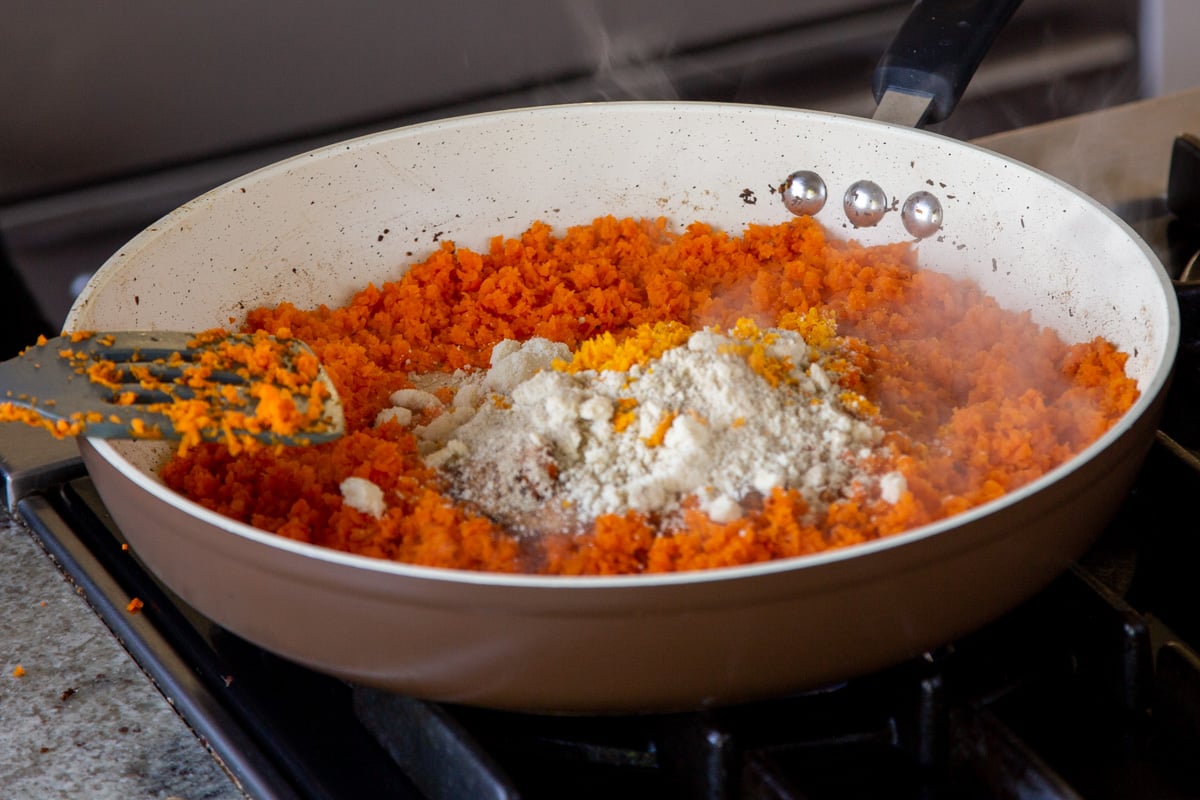 adding almond flour to the pan of grated carrots