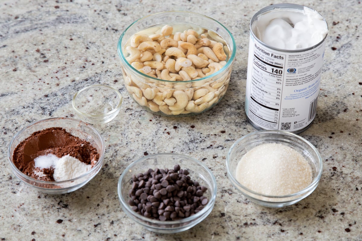 cashews, chocolate chips, and other pudding ingredients in bowls on a kitchen counter