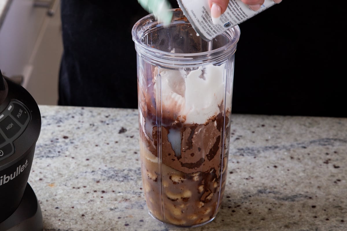 adding coconut cream to the blender with the other chocolate pudding ingredients