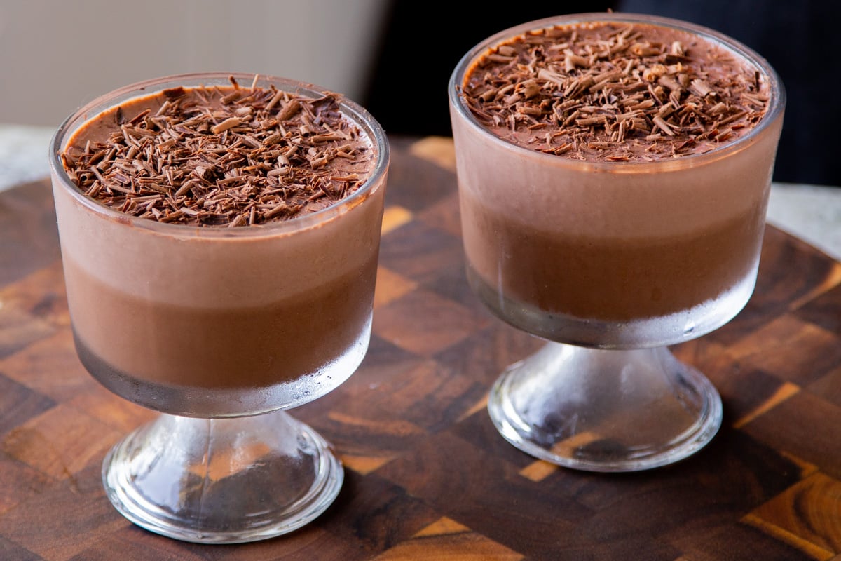 two cups of two-layer vegan chocolate pudding with chocolate shavings on top