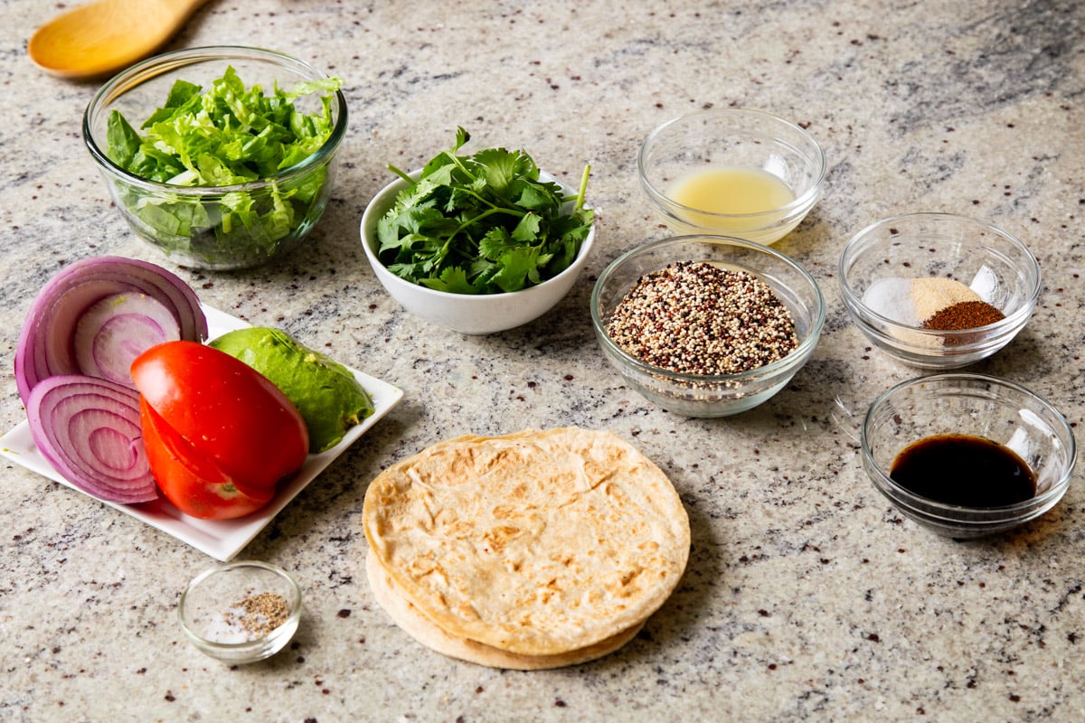 quinoa, tortillas, and other taco ingredients in bowls on a kitchen counter
