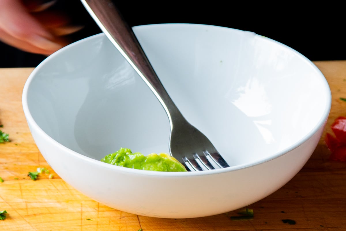 mashing the avocado in a bowl