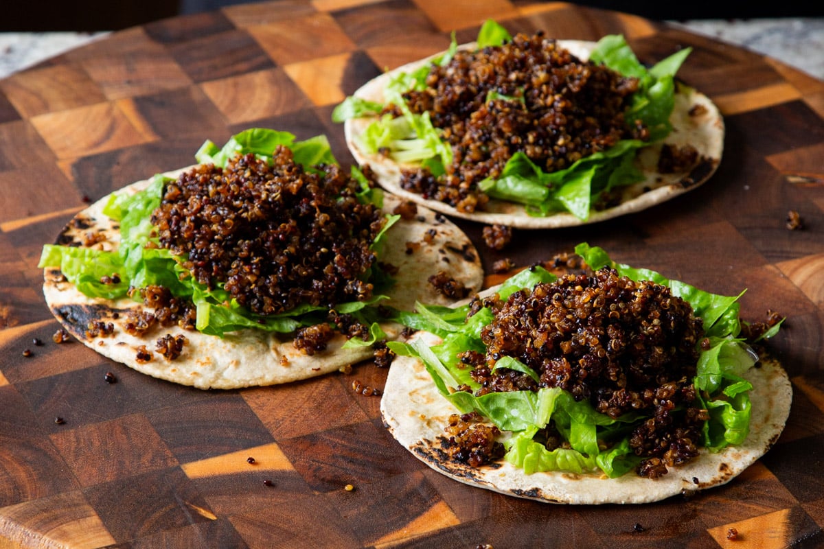adding quinoa taco meat to tortillas with lettuce