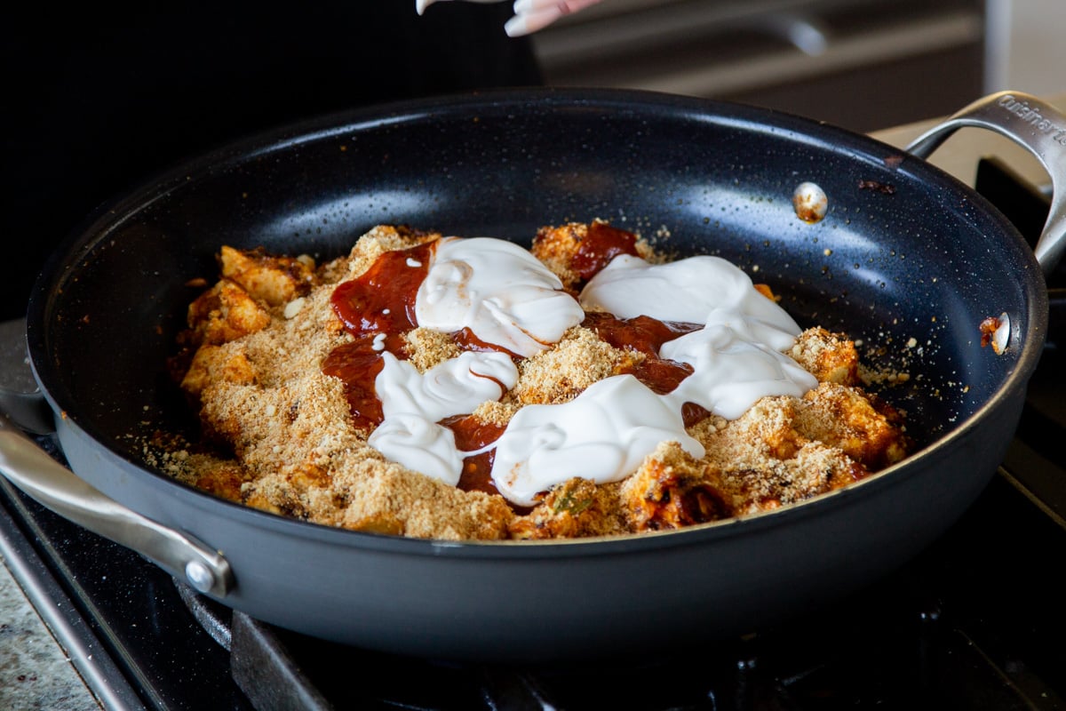 adding non-dairy yogurt and sambal oelek to the tofu mixture in the pan