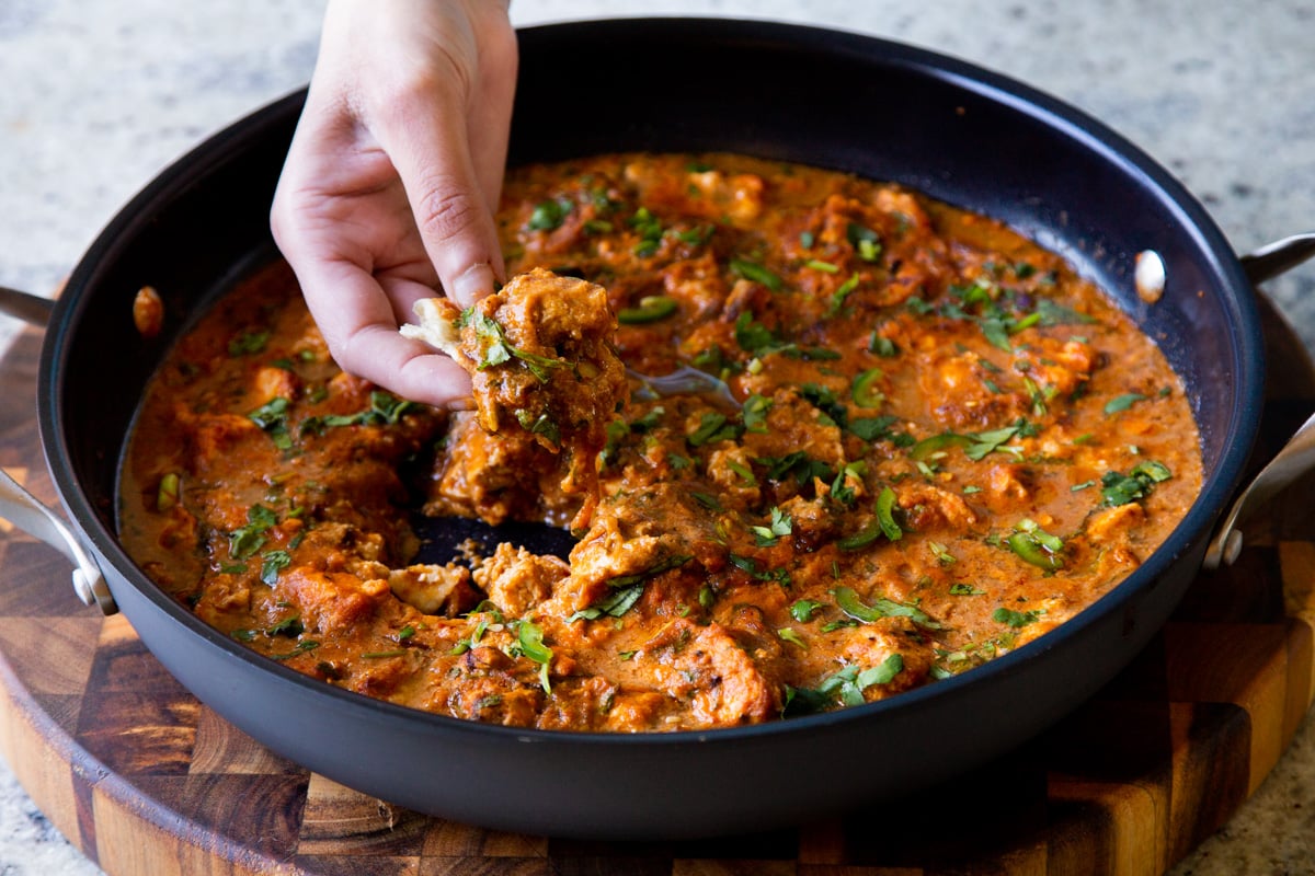 hand scooping up some Hyderabadi chicken curry on a piece of flatbread