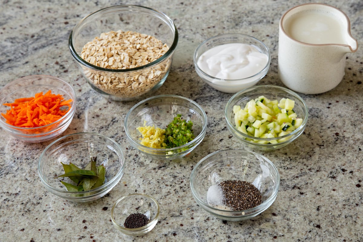oats, nondairy yogurt, and other Indian savory overnight oats ingredients in bowls on a kitchen counter